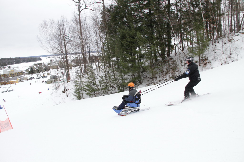 Volunteer tethering sit skier